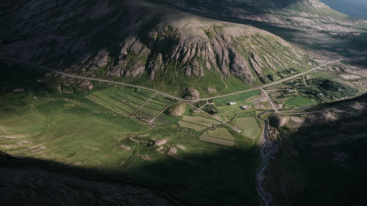 Aerial view of an Icelandic valley with fields, a river and a road in low evening sun